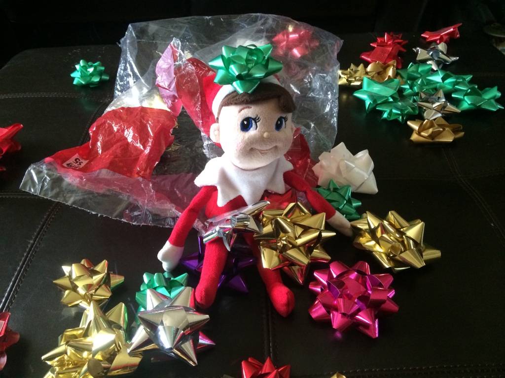a stuffed elf sitting in a pile of sticky Christmas bows